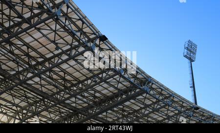 fragment d'un toit de stade avec un mât de projecteur haut sur un fond de ciel bleu clair, vue de dessous, éléments d'un extérieur urbain moderne Banque D'Images