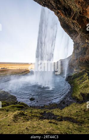 Vue sur la cascade unique Seljalandsfoss depuis le sentier qui mène autour de la grotte derrière la cascade, près de la route 1 / Ring Road, Islande Banque D'Images