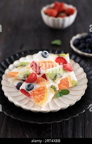 Bar à yaourt grec sain avec fraise, myrtille, kiwi et orange. Écorce de yaourt glacé sur la table en bois Banque D'Images