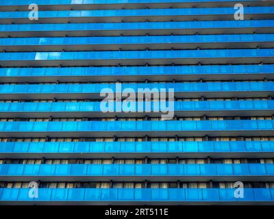 Fond des fenêtres d'un bâtiment moderne. Bâtiment haut. Beaucoup de fenêtres. Gratte-ciel, planchers. Fourmilière humaine. Auberge moderne. Balcons Banque D'Images