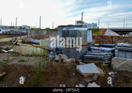 maçonnerie pour la construction de revêtements routiers. a proximité se trouvent des tuyaux métalliques, des cônes et d'autres éléments du chantier de construction. matériaux de construction couverts ag Banque D'Images