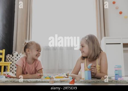 Enfants jouant avec des jouets colorés. Enfants assis sur la moquette dans la chambre à coucher ou la maternelle à la maison, la crèche. Jeu écologique éducatif pour enfant. Créatif heureux âge préscolaire enfant doux Banque D'Images