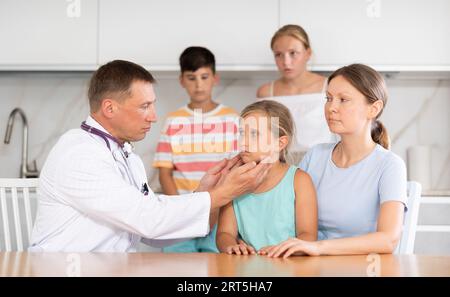 Homme médecin examine la gorge et les ganglions lymphatiques de la petite fille patient à la maison Banque D'Images