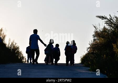 230910 -- GUIDING, 10 septembre 2023 -- lu Chengwen accompagne ses élèves pour rentrer chez eux dans le canton de Yanshan, dans le comté de Guizhou, dans le sud-ouest de la Chine, dans la province du Guizhou, le 6 septembre 2023. Yanjiao Teaching point est une micro école primaire située dans une zone plate parmi les montagnes dans le sud-ouest de la Chine s Guizhou. Lu Chengwen est le seul enseignant ici avec 28 élèves préscolaires et 6 élèves de première année. En 2012, lu, qui venait de sortir de l'université, choisit d'enseigner au point d'enseignement éloigné de Yanjiao. Les élèves d'âge préscolaire, issus du village montagneux de l'ethnie Miao, ne parlaient guère le mandarin Banque D'Images