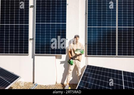 Technicien avec une tablette numérique sur un toit avec centrale solaire Banque D'Images