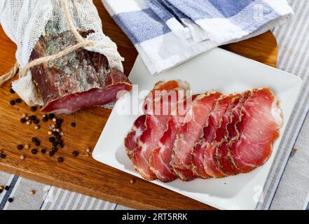 Tranches de porc de sirloin fumé sur une plaque de découpe en bois Banque D'Images