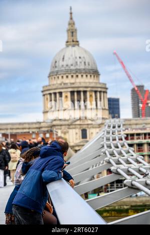 LONDRES - 24 avril 2023 : charme du paysage urbain : touristes sur le pont du millénaire à Londres, avec la cathédrale St Paul ajoutant une beauté historique au backdr Banque D'Images