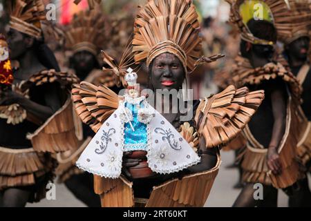 Femme tenant une figurine Santo Nino au festival ATI Atihan, Ibajay. Banque D'Images