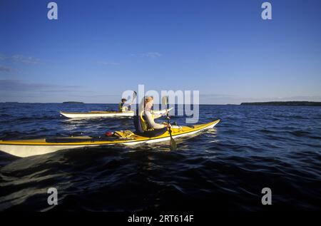 Deux femmes en kayak de mer au coucher du soleil, Muscongus Bay, Maine. Banque D'Images