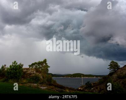 Des nuages de tempête spectaculaires s'accumulent au-dessus du rivage et se déplacent vers les îles de l'archipel de Kragero un jour d'été en août. Telemark, Norvège. Banque D'Images