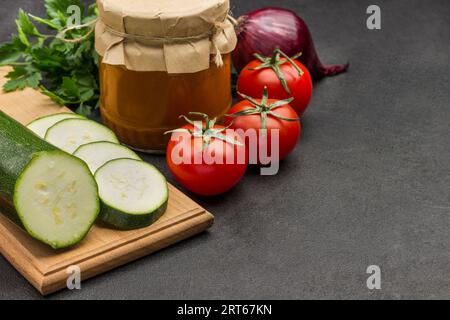 Courge en conserve étalée dans un bocal en verre. Légumes crus et épices : carottes, ail, oignons, tomates, poivre. Nutrition hivernale saine. Prod. Fermentation Banque D'Images