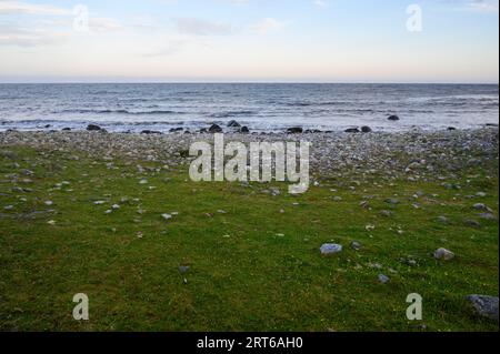 Vue du soir depuis la plage rocheuse sur l'île de Jomfruland jusqu'à une mer relativement calme avec des vagues douces se brisant. Telemark, Norvège. Banque D'Images