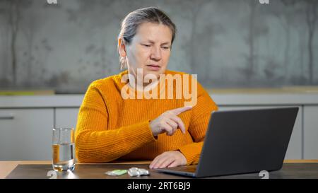 Femme mature lit prescription de pilules sur Internet sur ordinateur portable Banque D'Images
