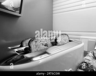 Une photographie classique en noir et blanc de quatre tranches de pain confortablement encastrées dans un grille-pain, mettant en valeur son design intemporel. Banque D'Images