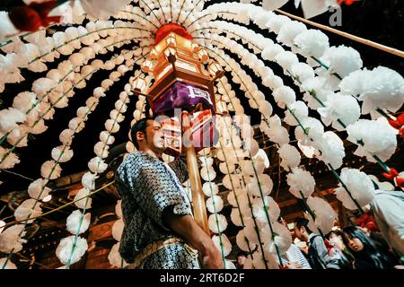 Tokyo, Japon. 12 octobre 2022 : les Japonais portent des lanternes sacrées ornées de fleurs de cerisier en papier au festival Oeshiki au temple Ikegami, Tokyo, Banque D'Images