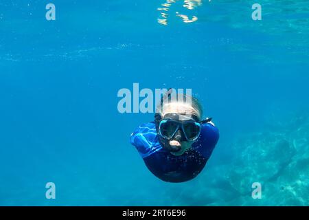 Un Homme tout en nageant librement dans le cristal clair de la côte illuminé par les rayons du soleil sous l'eau tout en plongeant dans la mer méditerranée cinque terre Mo Banque D'Images