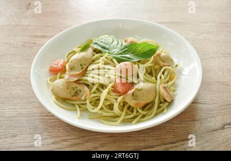 spaghetti sauté au pesto épicé avec saucisse en tranches et sauce basilic sur assiette Banque D'Images