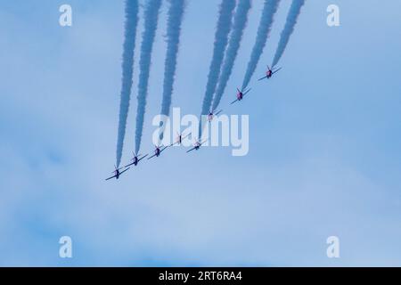 Un groupe d'avions en parfaite formation, volant à travers le ciel avec des contrails qui coulent derrière eux Banque D'Images