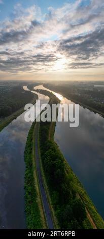 Découvrez la beauté à couper le souffle de la nature avec cette photo captivante d'un lever de soleil majestueux reflété dans deux cours d'eau immaculés. Le ciel de l'aube spectaculaire et coloré projette une lueur dorée sur les eaux ondulantes, créant une scène sereine et pittoresque. Ce paysage tranquille capture l'essence du petit matin, où le monde s'éveille à la première lumière du jour. Idéal pour transmettre un sentiment de paix et de beauté naturelle dans vos projets créatifs. Parfait pour une utilisation dans les voyages, le style de vie et les conceptions à thème environnemental. Majestueux Sunrise Reflection dans deux voies navigables. Photo de haute qualité Banque D'Images