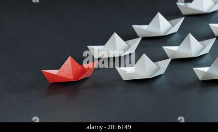 Concept de leadership. Le papier leader rouge est livré en tête parmi le blanc sur fond noir.rendu 3D sur fond noir. Banque D'Images