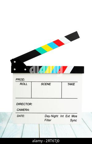 Clapperboard ou ardoise de film sur plancher en bois bleu avec fond blanc. Il est utilisé dans la production vidéo et l'industrie cinématographique. Banque D'Images