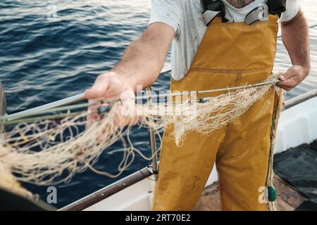 D'en haut récolté pêcheur mâle méconnaissable en uniforme seineur chassant le poisson avec le filet tout en travaillant sur la goélette à Soller près de Balearic Island of Mall Banque D'Images