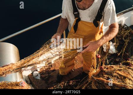 D'en haut récolté pêcheur mâle méconnaissable en uniforme seineur chassant le poisson avec le filet tout en travaillant sur la goélette à Soller près de Balearic Island of Mall Banque D'Images