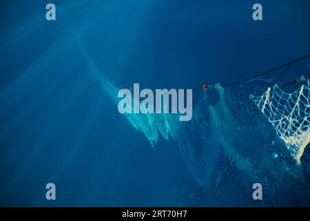 Grand filet avec des cordes flottant dans l'eau de mer bleu profond sous la lumière du soleil pendant la pêche traditionnelle à Soller Banque D'Images