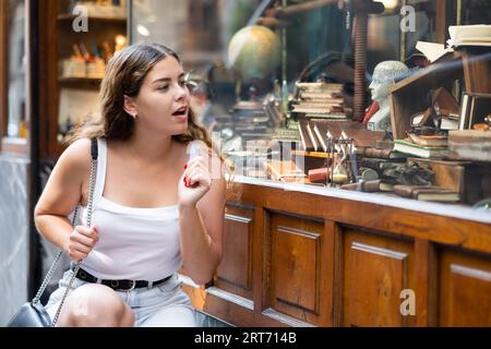 Une jeune femme intéressée regarde des articles de papeterie de style rétro dans un magasin de souvenirs Banque D'Images