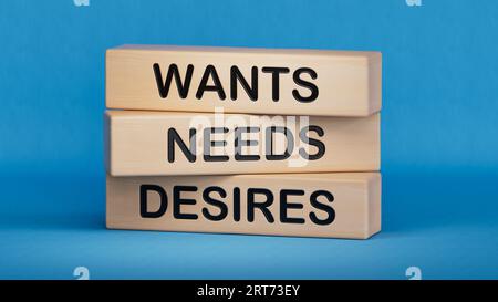Veut et désire symbole. Concept Words veut besoins désirs sur des blocs de bois. Main d'homme d'affaires. Les besoins et les désirs des entreprises, psychologiques Banque D'Images