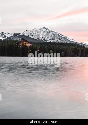 Photo verticale de beau lac dans le paysage d'automne avec des montagnes enneigées étonnantes sur le fond. Strbske pleso dans les Hautes Tatras à l'automne avec reflet de l'eau Banque D'Images