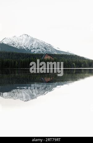Photo verticale de beau lac dans le paysage d'automne avec des montagnes enneigées étonnantes sur le fond. Strbske pleso dans les Hautes Tatras à l'automne avec reflet de l'eau Banque D'Images