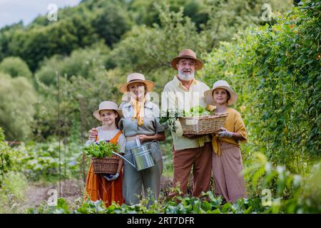 Portrait de grands-parents avec des petites-filles récoltant des légumes à l'automne. Banque D'Images