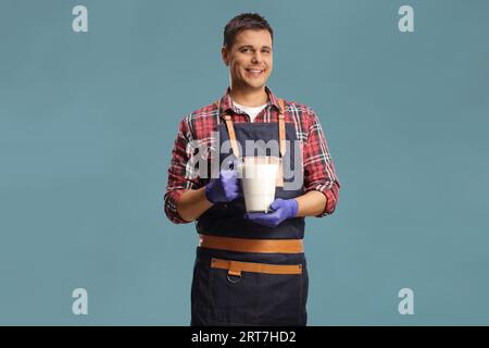 Fermier tenant un pot de lait et souriant isolé sur fond bleu Banque D'Images