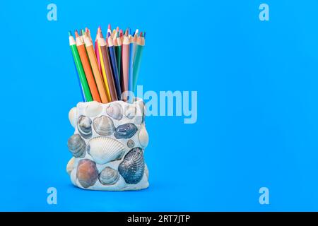 Porte-crayon créé avec de la pâte à sel et des coquillages sur un fond bleu Banque D'Images