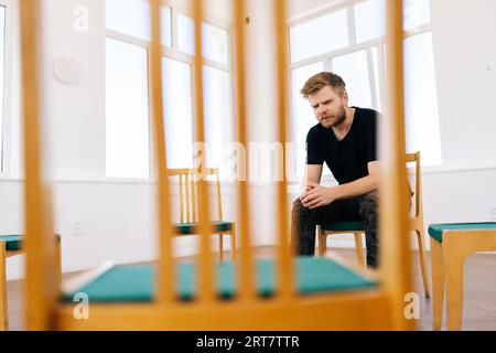 Vue à distance d'un soldat déprimé parlant d'un traumatisme au cours d'une séance de psychothérapie de groupe. Jeune homme barbu vétéran parlant pendant le soutien de TSPT Banque D'Images