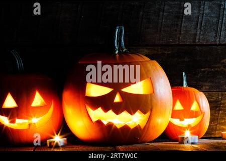 Trois lanternes de citrouille d'Halloween et bougies allumées sur fond de bois foncé Banque D'Images