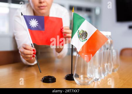 Fille méconnaissable pose des drapeaux midget du Mexique et de Taiwan avant les négociations internationales Banque D'Images