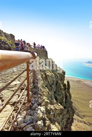 Lanzarote, Îles Canaries, Espagne - 25 mars 2023 : touristes au bord d'une falaise, profitant de la vue sur l'île de la Graciosa depuis Mirador del Rio. Banque D'Images