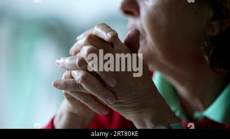 Gros plan des mains âgées serrées dans la contemplation. Langage corporel pensif d'une femme âgée dans la vieillesse des années 70, main de détail Banque D'Images