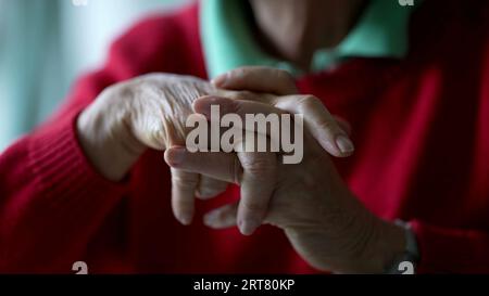 Gros plan des mains âgées serrées dans la contemplation. Langage corporel pensif d'une femme âgée dans la vieillesse des années 70, main de détail Banque D'Images