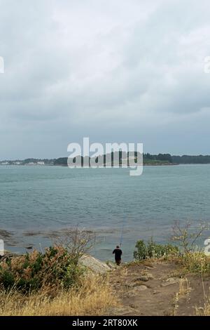 Pêcheur et vue sur l'Ile de Gavrinis depuis la Pointe du Monteno, Arzon, Morbihan, Bretagne, France Banque D'Images