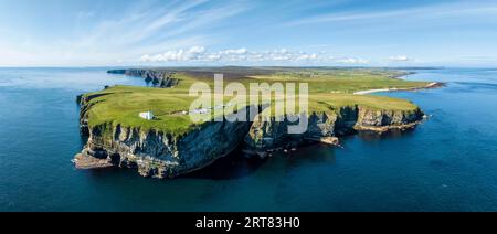 Panorama aérien du paysage côtier accidenté à Duncansby Head avec le phare, derrière lui la formation rocheuse Duncansby Stacks, à droite Banque D'Images