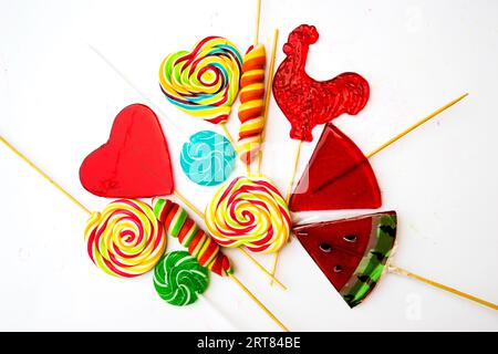 Bonbons différents. Bâtons de gomme et divers lollipops isolé sur fond blanc. Vue d'en haut. Banque D'Images