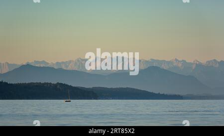 Petit voilier sur le lac Starnberg près de Bernried en haute-Bavière en été au lever du soleil avec les Alpes en arrière-plan Banque D'Images