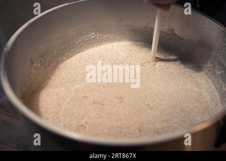 Agitation de la purée dans un grand fût en acier inoxydable pendant le processus de bière à la maison dans le garage Banque D'Images