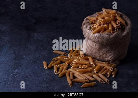 Pâtes séchées à grains entiers pour une alimentation saine, faible, fond sombre Banque D'Images