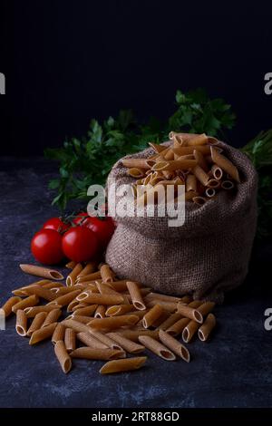 Pâtes séchées à grains entiers pour une alimentation saine, faible, fond sombre Banque D'Images