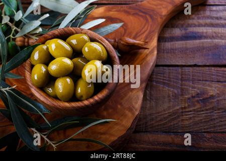 Olives vertes en bois d'bol sur fond en bois ancien. Vue de dessus avec l'espace pour le texte Banque D'Images