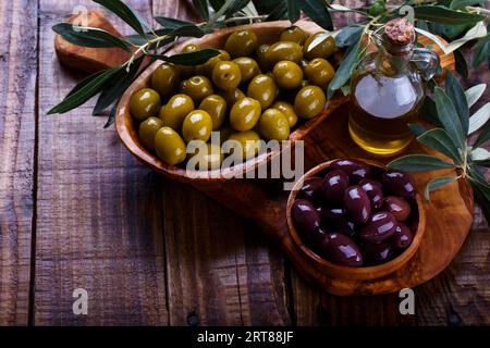 Olives vertes et noires en bois d'anciennes coupes sur fond de bois. Vue de dessus avec l'espace pour le texte Banque D'Images